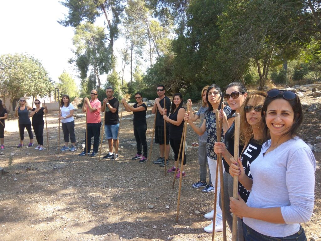 עומדים במעגל עם מקלות במהלך יום גיבוש לעובדים